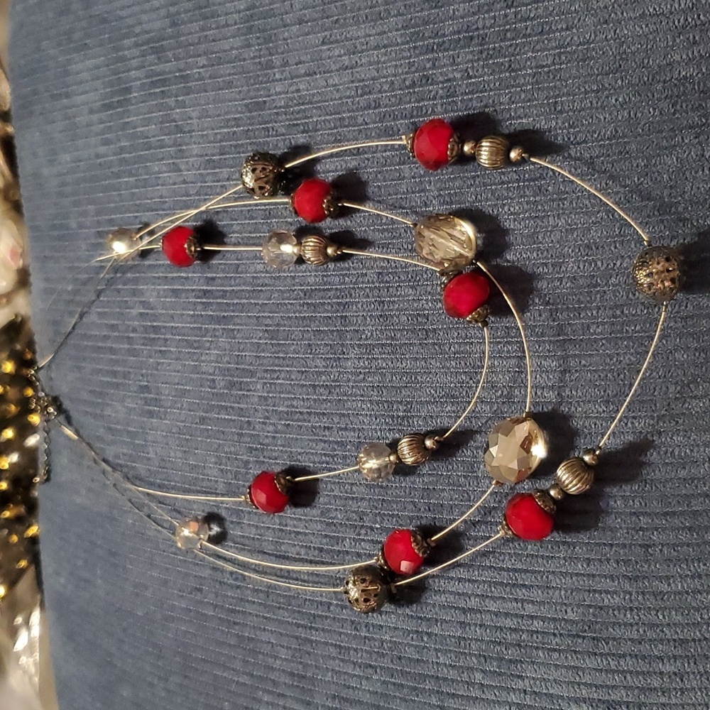 Three strand costume necklace with red, clear and black beads on a wired chain.